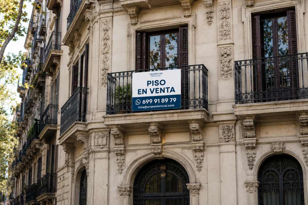 Historic stone building with ornate facade and a balcony sign reading 'PISO EN VENTA' in blue and white.
