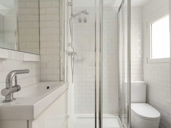 Bright white bathroom with a glass-enclosed shower, white subway tiles, and a white vanity.