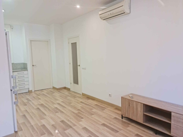 Modern white interior with light wood laminate flooring, two white doors, and a wall-mounted air conditioner above; a wooden console sits along the wall.